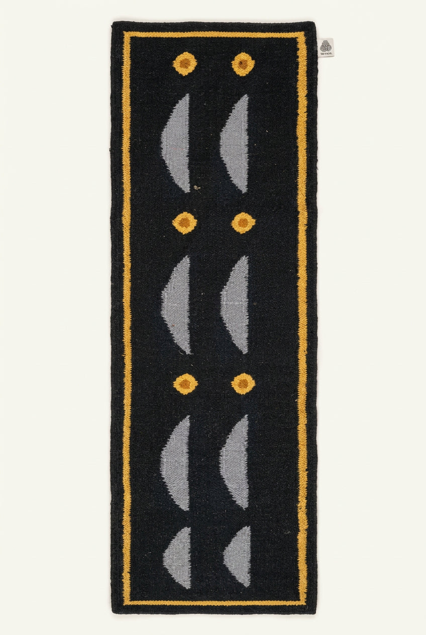 A long, narrow navy blue hand woven rug with a yellow border, white curved geometric motifs, and small yellow circular accents.