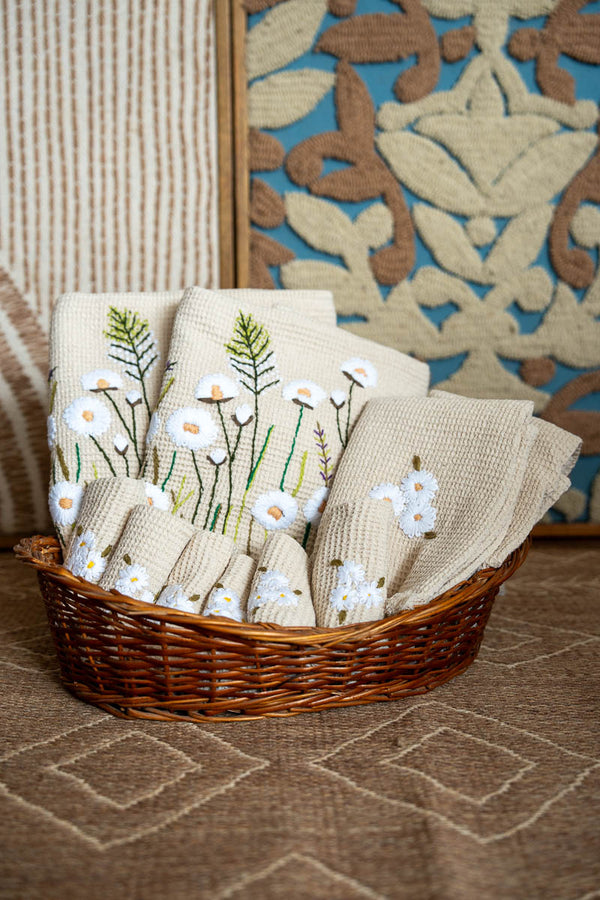 Basket of embroidered towels with floral patterns on a textured surface