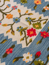 A woven textile with a floral pattern on a blue and off-white background, showing red, blue, orange, yellow, and green details.