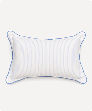 A white rectangular lumbar pillow with vertical pinstripes and a thin blue piped border, shown against a light off-white background.