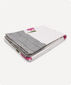 A folded white textile item, likely a blanket or throw, featuring a black and white striped pattern on one side and small pink floral accents with green stems.