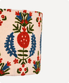 A close-up of a cylindrical container or vase with a cream-colored fabric cover featuring a colorful embroidered or printed floral pattern with red, blue, and green motifs.